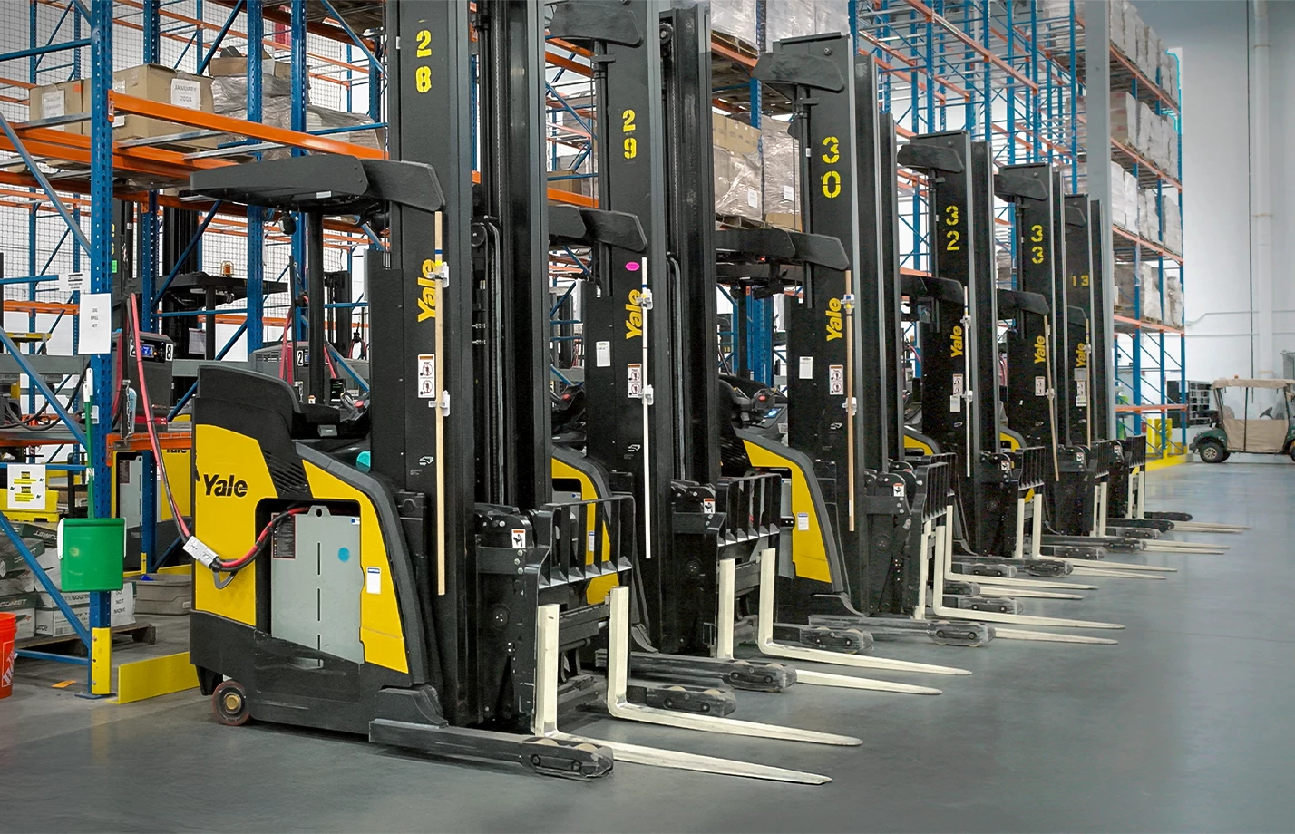 A row of Yale electric lift trucks recharging in a warehouse.