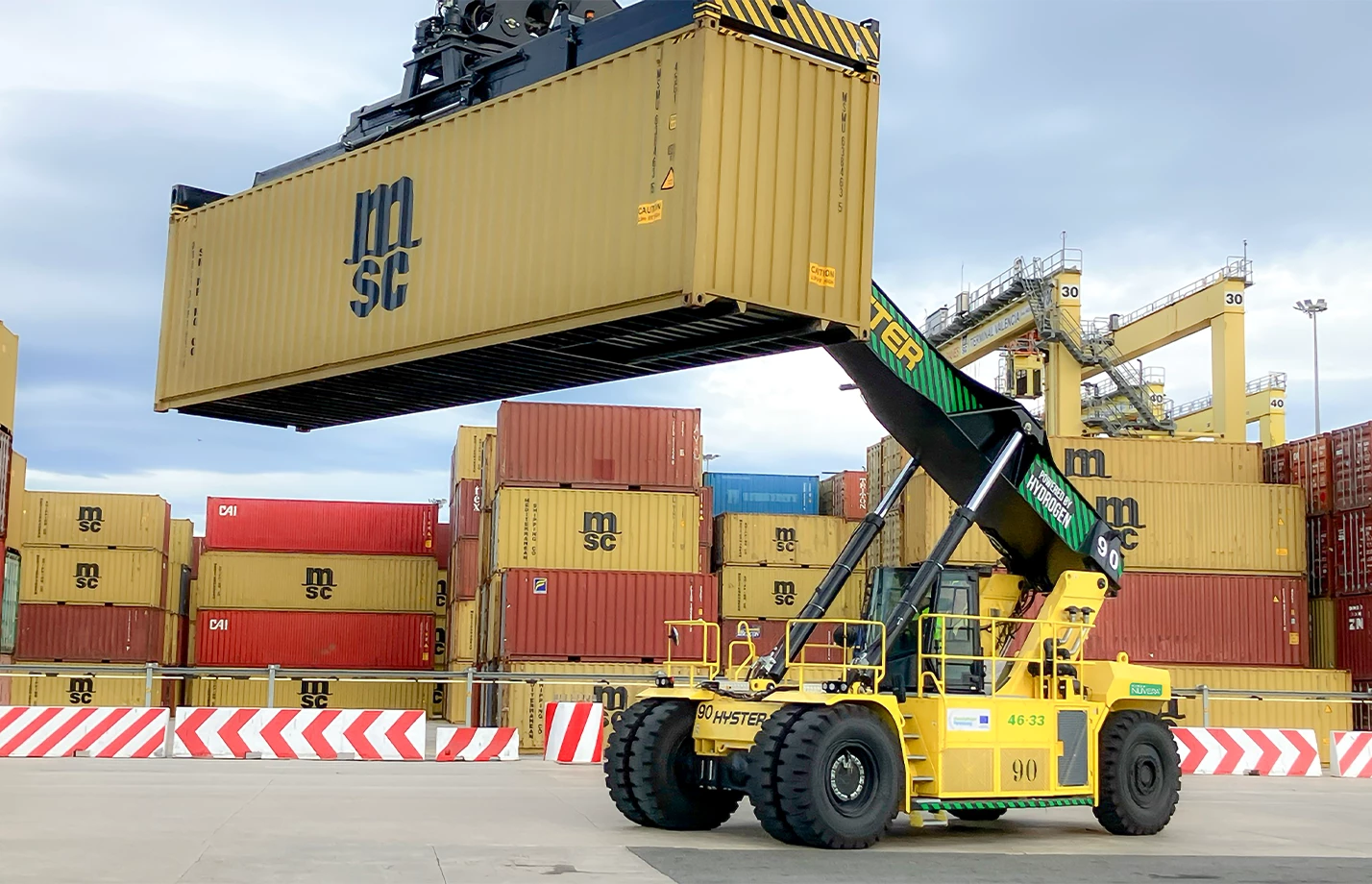 Hyster hydrogen fuel cell Reachstacker lifting a cargo container at a seaport.