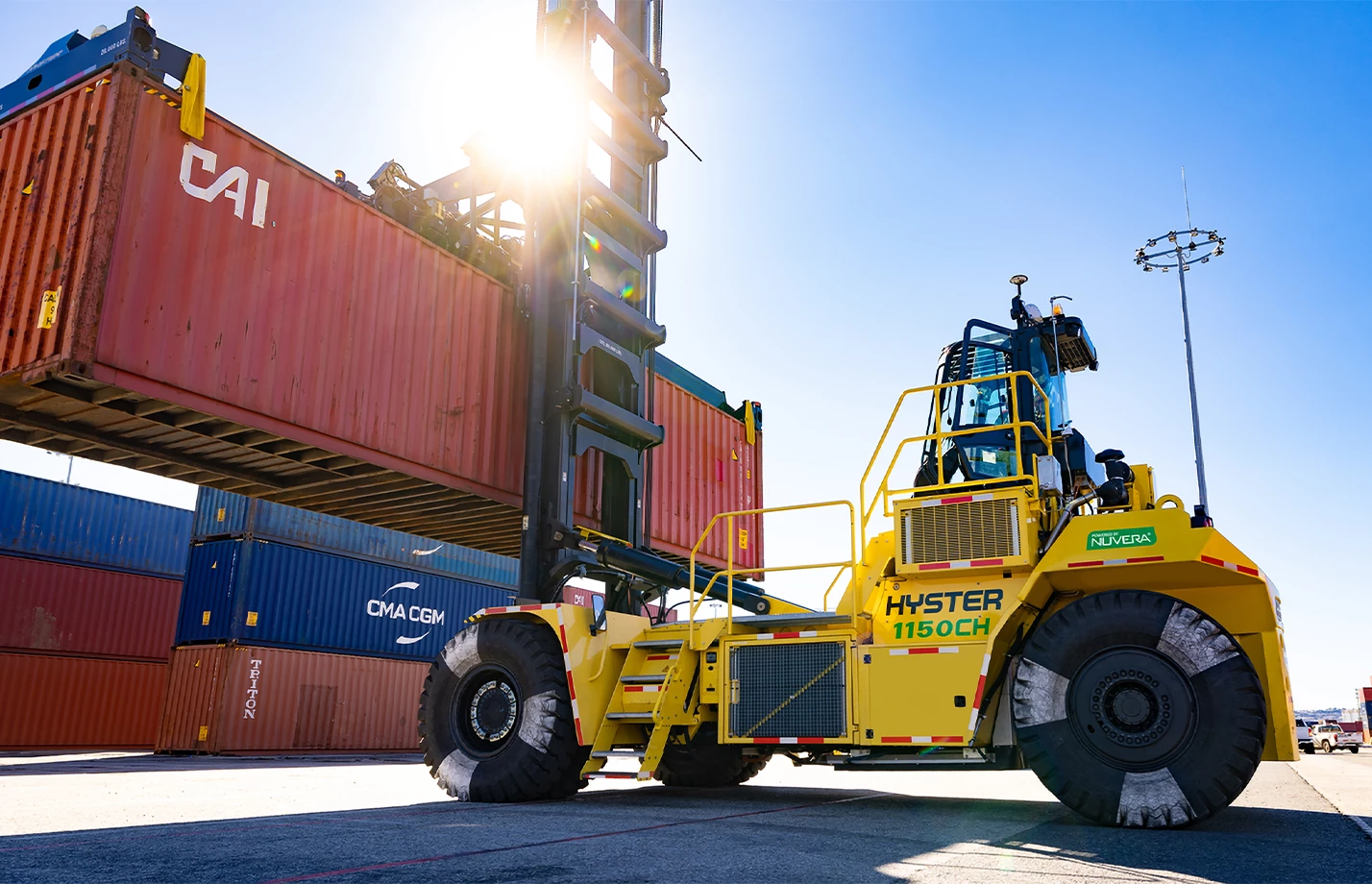 Hyster HFC Reachstacker lifting a cargo container at a seaport.