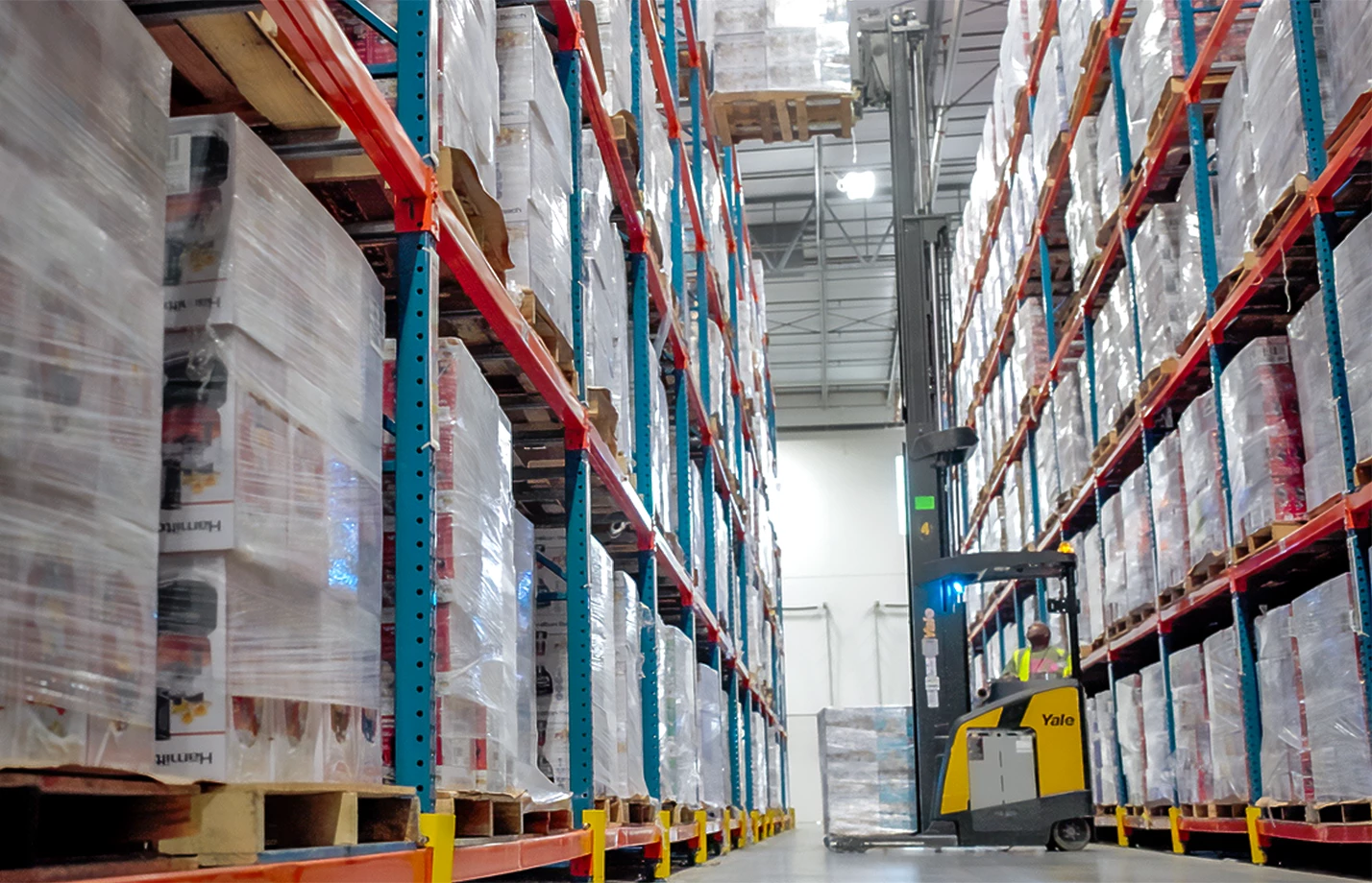 A Yale narrow aisle reach truck working at height inside a large warehouse.
